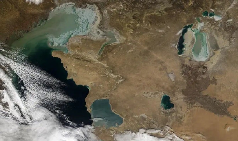 Imagem espacial mostra o Cáspio parcialmente coberto por nuvens. À direita, o que resta do Aral, fragmentado em duas partes.NASA