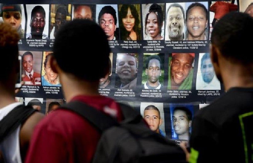 Em protesto após um ano da morte de Michael Brown, manifestantes estendem cartaz com foto de pessoas que foram mortas pela política