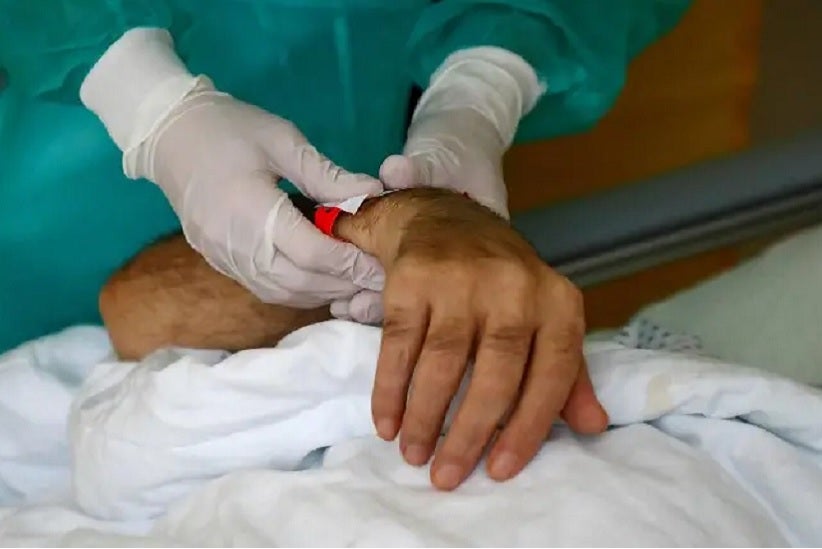 Una enfermera sostiene la mano de un enfermo de la covid-19 en un hospital en Berlín FABRIZIO BENSCH (REUTERS)