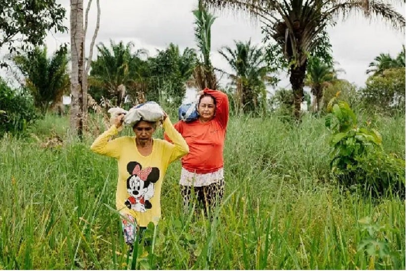 Doña Ivonete y su vecina acarrean los cocos en la cabeza. KRISTIN BETHGE